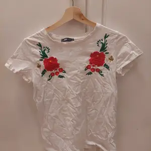 En vit t-shirt med en broderad blomma och humla. Den är i bra skick.  25kr+frakt