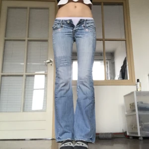 Y2k jeans med blommor - Bootcut jeans med fina blomdetaljer💝Väldigt bra skick 💎 Märkta storlek 38, uppskattas mkt mindre, typ storlek W27. Dom är väldigt låga. 81 cm runt midjan, 81 cm innerbenslängd.💎Jag är 176 cm och har W29 i jeansstorlek 💛Endast frakt ✨Använd gärna köp nu<3