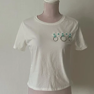 Vit t-shirt med blommig detalj - Helt oanvänd vit t-shirt med blom-detaljer i storlek S för 25kr. 💗
