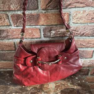 Röd handväska i medelstorlek💕   Den är ca 27cm i bredden, och 15-20 cm i höjden beroende på vart man mäter, samt ca 43 cm från axelbandet till botten på väskan💕