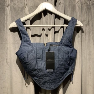 Korettopp i jeans, Nyskick - Oanvänd korsetttop från lioness. Köpte denna coola topp för omkring ett år sen med har tyvärr aldrig blivit att jag använt den. Nypris låg vid omkring 400