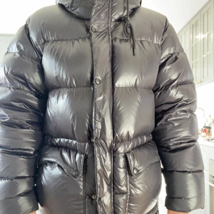 Svart glansig dunjacka  - Säljer min dunjacka i shiny svart färg. Storlek S , men stor i storleken , så om du har M funkar den också. Unisex jacka. 100% RDS märkt dun .  Ordinarie pris 1650