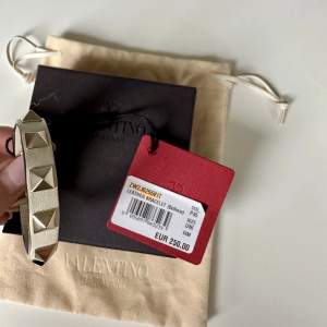 Unikt Valentino armband i färgen  ”off white” med guldiga nitar, helt nytt! Medföljer låda, dustbag samt extra nitar. Kvitto finns! 
