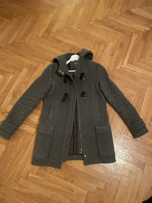 Kappa från Massimo Dutti  - Grå kappa från Massimo Dutti! Sparsamt använd. Står ej storlek i kappan men strl xs/s.  Nypris runt 2000kr