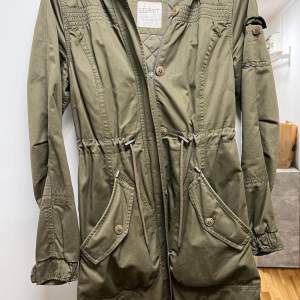 En lång militär-färgad lång jacka från märket ESPRIT. Har i princip aldrig använt den då den inte passar på mig och hade ingen ångerrätt på den. STORLEK: M, 40