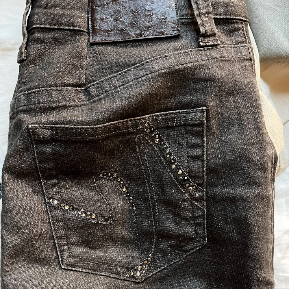 Ett par bruna lågmidjade jeans med coolt pärlmönster på fickorna.  Midjemått: 68 cm Innerbenslängd 74 cm Passar mig som är 160 cm och vanligtvis har S i byxor, skriv om du har några funderingar!. Jeans & Byxor.