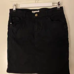 En svart stretchig jeanskjol från Cubus i storlek L.