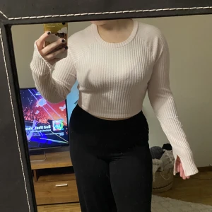 Tröja - En puderrosa stickad tröja med slits vid slutet av ärmarna.