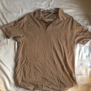 Brun pikétröja  - Mjölkchokladbrun piketröja från en underground outlet i  .  Storleken är S, modellen på bild 3 är 185 cm lång.