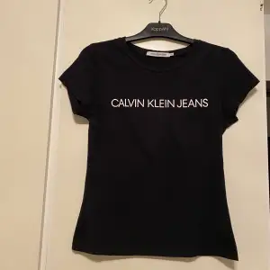 En svart t-shirt med vitt tryck på brösten från Calvin Klein. Enbart använd vid att tillfälle. 