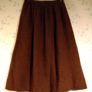 Brun kjol i angora/ull - Den här vackra bruna midikjolen är så varm och skön! Ytterlagret är i angora och ull. Den har fickor i sidorna, är midilång och har dragkedja + knapp i ryggen. Ett gummiband är påsytt vid knappen. Obs det står att den är st38 men är smal i midjan! 