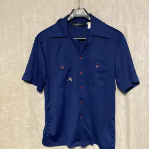 Blå skjorta med röda knappar och en gullig anka