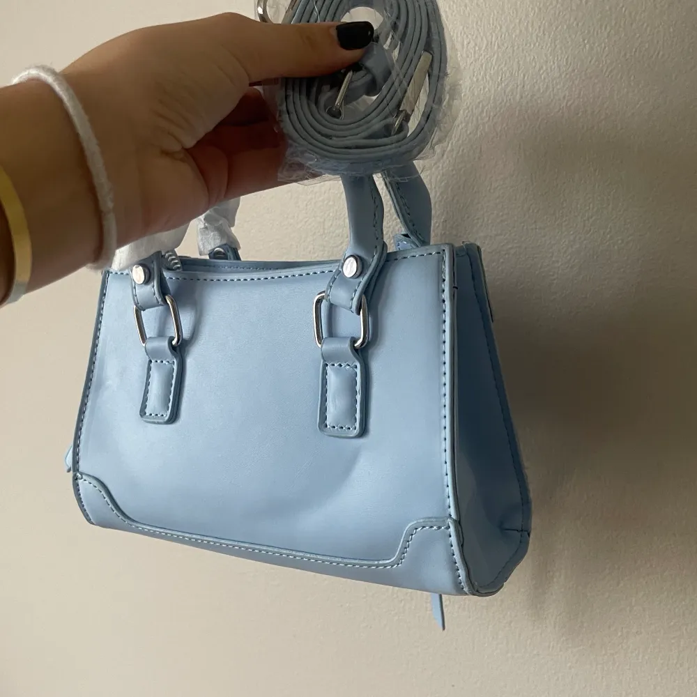 Liten ljusblå söt väska ifrån SHEIN, aldrig använd och den har nog legat i min garderob i ett år. Man får också med ett långt band, säljes pga kommer ej till användning. Väskor.