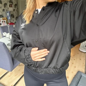 Adidas jacka i strl 38 - Riktigt snygg bomber jacka från adidas. Sport materialet med blått foder inuti.