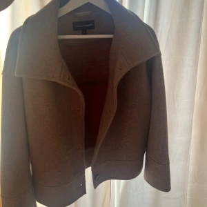 Kort kappa - Säljer denna begie/brunna korta kappan från Kappahl. Det är bara använd ett fåtal gånger föra året och är i fint skick. Stl M