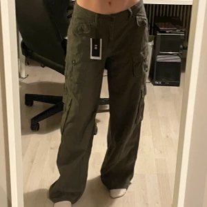 Lågmidjade byxor  - Grå/gröna lågmidjade byxor från Emmiol, köpta för 600kr. Dom är för stora för mig så derför dom långa vid benen. Kom med ett band runt som man kan knyta runt midjan💕
