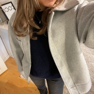 Kort kapp NA-KD  - Säljer denna populära korta kappan i grå från NA-KD. Köpt förra julen, sparsamt använd. storlek 36, köparen står för frakten 66kr spårbar 