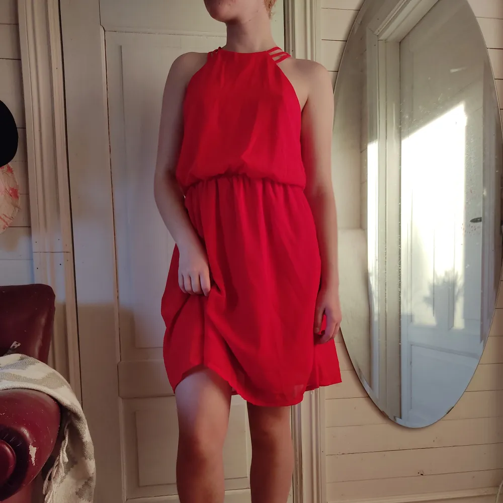 En starkt röd klänning med en öppning i ryggen. Klänningen har bara blivit använd typ en gång.. Klänningar.
