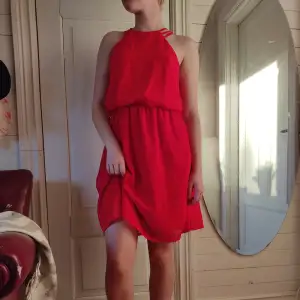 En starkt röd klänning med en öppning i ryggen. Klänningen har bara blivit använd typ en gång.