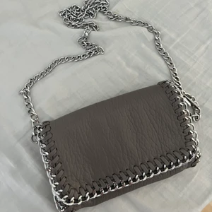 Tiamo väska - Säljer denna axelbands väska från Tiamo i färgen grå. Säljer pågrund av att jag har för många axelbandsväskor. Säljes för 200kr inkl frakt<3