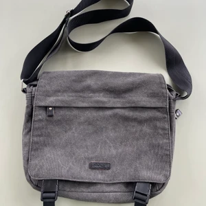 Skitsnygg väska - Denna väskan är så snygg, fin grå färg med svarta detaljer. Massa olika fickor, man kan ha den crossbody och den är perfekt till skolan!!