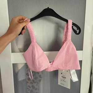 Topp - Kort ljus-/babyrosa topp i skjortmaterial. Speciella/coola band. Köpta på behrska för 99 kuna i Kroatien vilket motsvarar ca 150 svenska kronor. Aldrig använd och har prislapp kvar. Cool under kavaj?