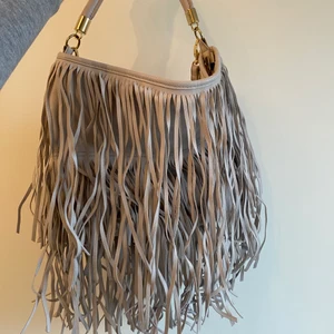 Fransväska - Ljusgrå fransväska från H&M. I bra skick då jag använt den kanske en gång. Köparen står för frakt annars kan jag mötas upp i Nacka forum eller Östermalmstorg 🤍