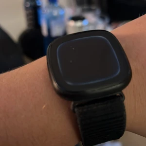 Fot bit versa 3 - Använd fåtal ggr, inte något jag trivdes med men det fungerar felfritt har legat och dammat rätt länge. Tygband med kardborre i både svart och lila/grå