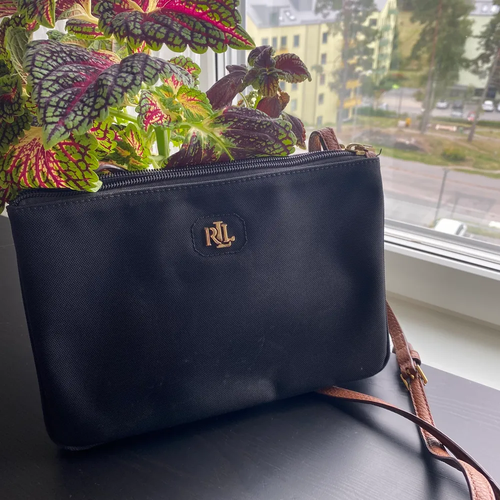 Cross body bag från Ralph Lauren i svart med brunt axelband. Lite slitet skick men inga märkbara skador. Dubbla fack med kortfack i ena.. Väskor.