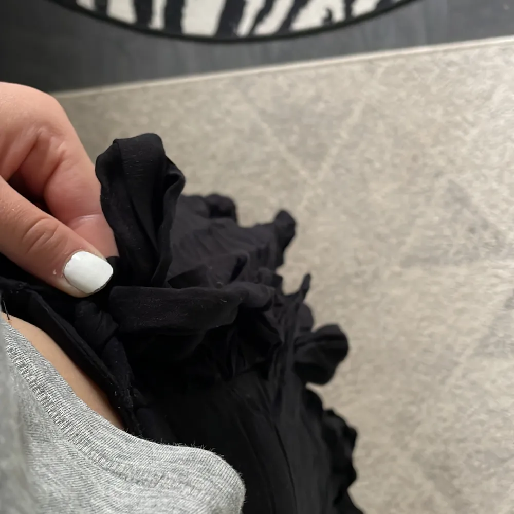 Jag säljer en svart volang kjol som är från Lindex. Den är använd men i bra skick. Den har knytning på sidan.. Kjolar.