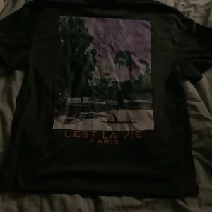 Oversized T-shirt  - En mörkgrå t shirt med tryck på ryggen. Det är storlek xs men sitter oversized på mig som brukar vara S/M