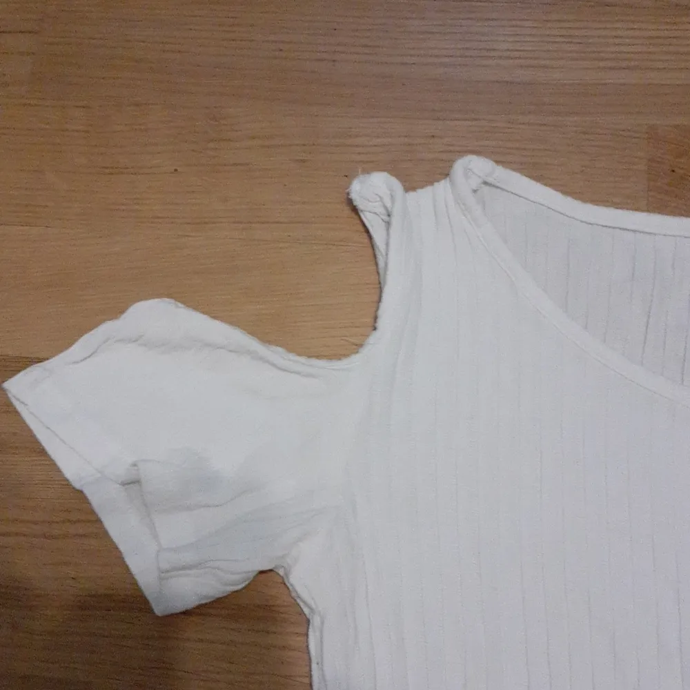 En fin vit t-shirt med ihåliga axlar som passar in i sommarn som kommer om ett tag. Har ingen användning av den så därför säljer jag :). T-shirts.