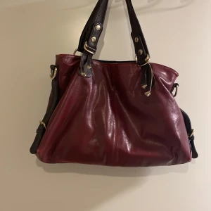 Väska - En oanvänd väska från secondhand. Den är vinröd med mörk brun band. Jätte bra skick ❤️tryck INTE på köp nu💋Dirket pris 500+frakt👄