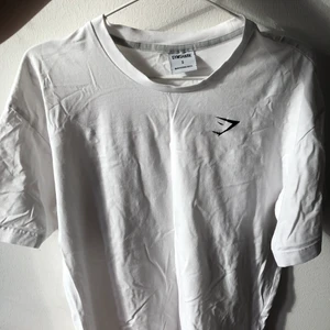 Gymshark träningstshirt - Vit - Oversized träningstshirt från herravdelningen i ett mycket behagligt material. Är i mycket fint skick och säljes p.g.a dubbla exemplar! 💗