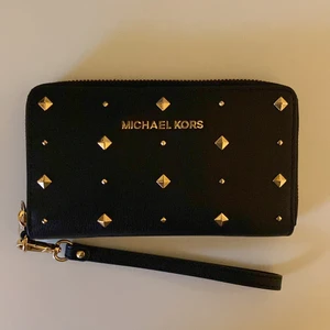 Plånbok Michael Kors - Rymlig plånbok i svart med guldiga nitar. Helt oanvänd.