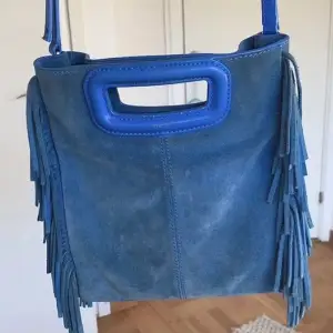 Säljer denna fina maje väska i stora modellen och blå färg. Den är väll använda men fortfarande fint skick. Säljer då jag vill köpa en ny i annan färg. Den blåa läderbandet ingår. 