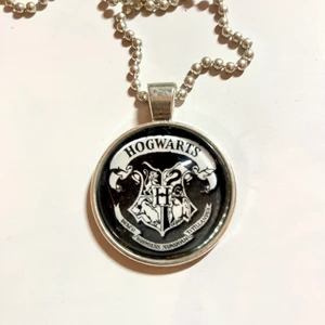 Hogwarts Halsband Harry Potter - Nice halsband med Hogwarts loggan, handgjort av mig. Själva berlocken mäter ca 2,5cm och sitter på en ca 30cm lång kedja (stängd), kan korta kedjan till önskad längd! Vanligt frimärke går på 13kr. Se sista bild för allmän info ❤️