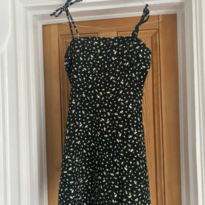 Småblommig svart klänning H&M - Svart småblommig klänning från H&M Divided, knytbara axelband