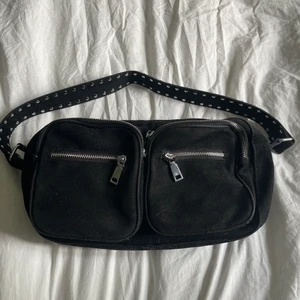 Väska - Superfin svart väska från Noella. Några knappar på axelbandet har lossnat men ser ut som ny (skriv för bilder)! Långt axelband tillkommer