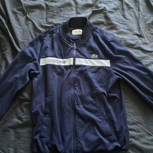 Lacoste zipper - En mörk blå Lacoste zipper i hyfsat skick  