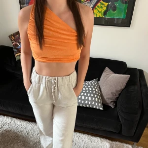 One Shoulder Top - En orange top i storlek M. Knappt använd och ganska liten i storlek så passar även Xs/S. Frakt ingår ej
