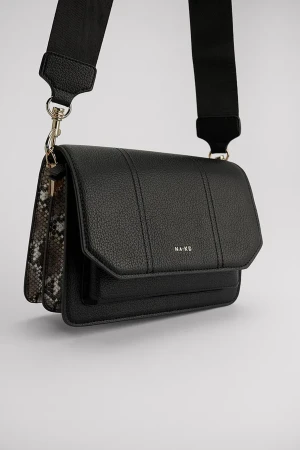 NA-KD crossoverväska - En väska från Nakd i mycket bra skick. Har ”ormmänster” som detaljer på sidan av väskan. Köpt för 499kr. Medföljer en justerbar svart axelrem. 