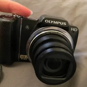 Olymous kamera 18X wide, funkar utmärkt och har många tillgängliga inställningar som går att ändra på, laddare och fodral medkommer. Material kan enkelt föras över till dator med hjälp av USB.