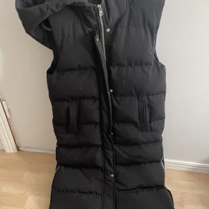 Chiquelle - Lång höst väst som är tjock och har luva och fickor. användts fåtal gånger men är som ny. Helt felfri och rökfri