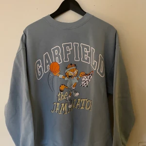 Ljusblå oversised sweatshirt med tryck garfield.  - Fint skick, tvättad och ser oanvänd ut. Bekväm med mjukt foder på insidan. Storlek M men passar båda mindre och större. 