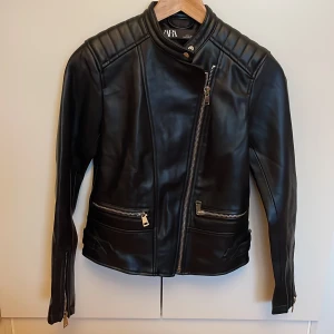 Svart fejkskinnjacka från Zara - Svart jacka i konstgjort läder från Zara, använd 1 gång. Storlek XS. Kan mötas upp i Uppsala annars står köparen för frakten! ☺️