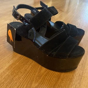Platå klackar, ny med lapp - Platåskor, nya med lappar kvar. Klackar ca 10-12 cm, har inte mätt. Strl 36. Från city bird. Köparen står för frakten