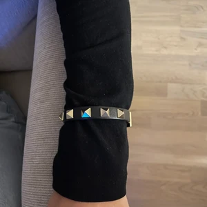 Valentino Armband  - Säljer mitt Valentino armband som tyvärr inte kommer till användning längre. Inga specifika skador. Endast använt några gånger. Svart med guldiga nitar. Box kommer med. Skriv för fler bilder❣️❣️ Kan max gå ner 1100 inkl frakt då