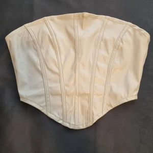 Beige korsett/topp stl XS - Beige korsett/topp i skinnimitation, stl XS. Dragkedja ibak. Söm låstnat liiite (se sista bild). Aldrig använd. Köparen står för frakten. 🤍 