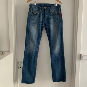 True Religion lågmidjade jeans - Ett par skitsnygga lådmidjade äkta True Religion jeans, köpta på en vintage affär i New York! Är typ bootcut, sitter åt i låren och lösa efter knäna. Står ej vilken modell. Antar att 30 som står på lappen är storleken :)  Är i jättebra skick! Säljer pga för små för mig tyvärr😭 Köparen står för frakten annars kan jag mötas upp i Göteborg! 💕✨